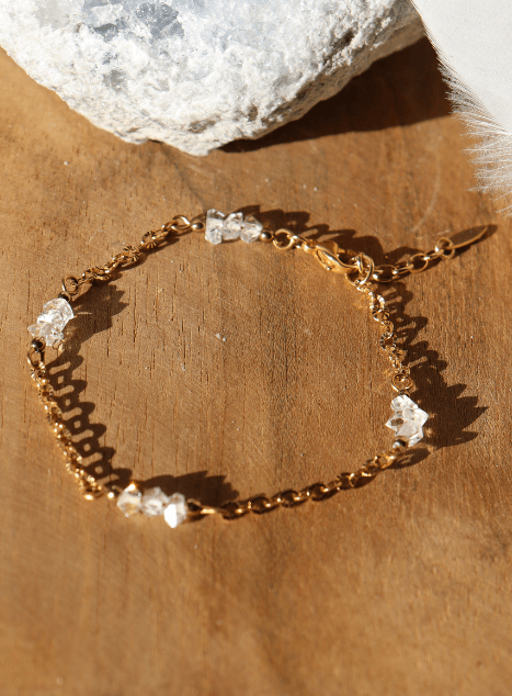 Bracelet Lulu en acier inoxydable doré orné de cristaux de diamant d’Herkimer, bijou raffiné et lumineux présenté sur fond en bois naturel.
