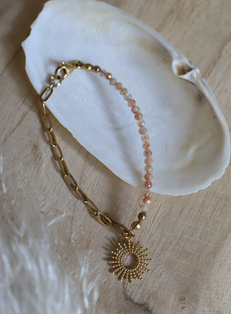 bracelet-chacha-pierre-de-soleil-pendentif-soleil-acier-inoxydable-dore.jpg Bracelet Chacha en acier inoxydable doré avec perles de pierre de soleil et pendentif soleil, bijou lumineux présenté sur coussin en lin dans un coquillage