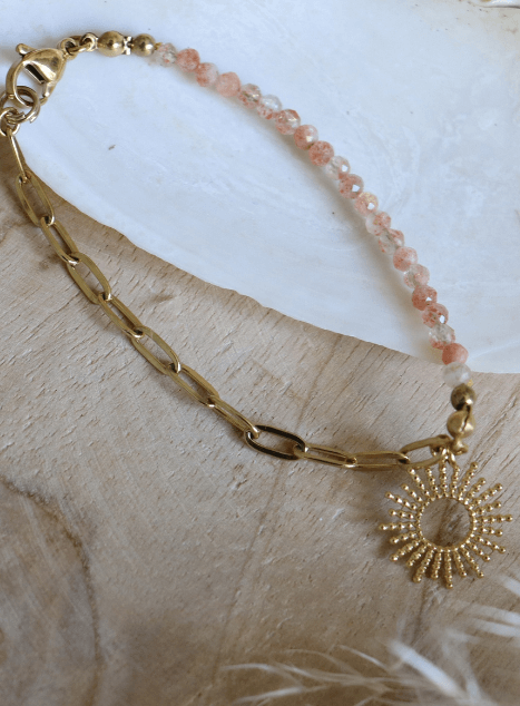 bracelet-chacha-pierre-de-soleil-pendentif-soleil-acier-inoxydable-dore.jpg Bracelet Chacha en acier inoxydable doré avec perles de pierre de soleil et pendentif soleil, bijou lumineux présenté sur coussin en lin dans un coquillage