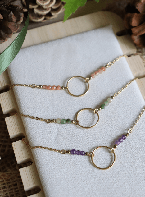 Trio colliers cercles et pierres naturelles Trois colliers en acier inoxydable doré avec pendentif cercle et perles de pierres naturelles — améthyste, jade verte et pierre de soleil