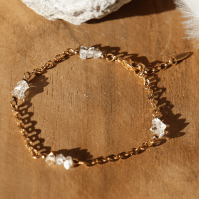Bracelet Lulu en acier inoxydable doré orné de cristaux de diamant d’Herkimer, bijou raffiné et lumineux présenté sur fond en bois naturel.
